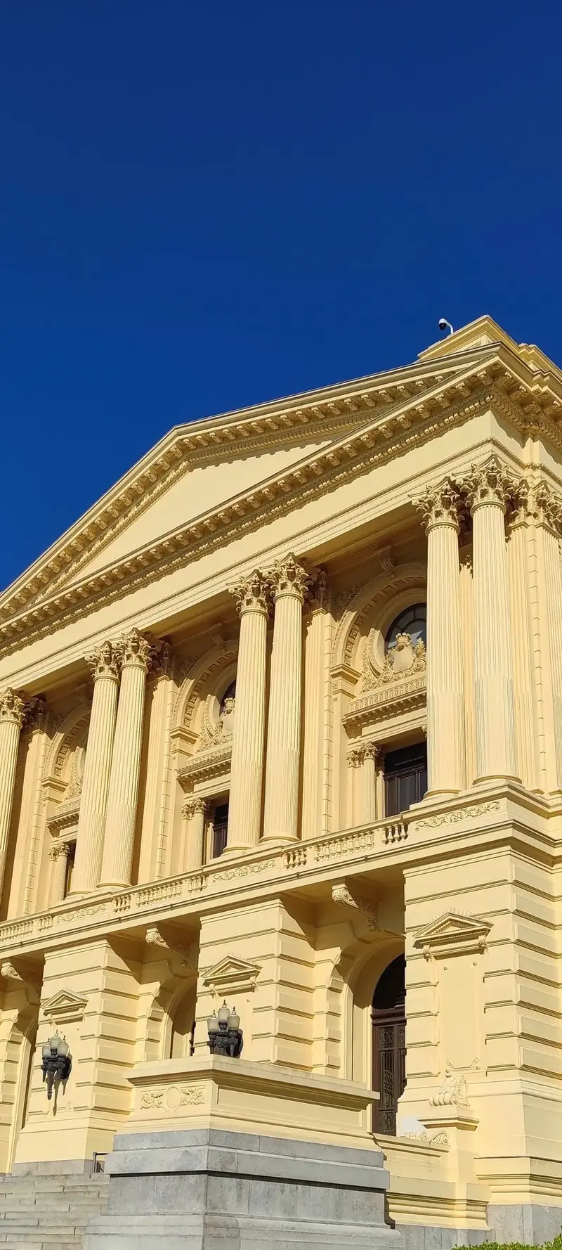 Fachada neoclássica amarela do Museu do Ipiranga sob céu azul profundo