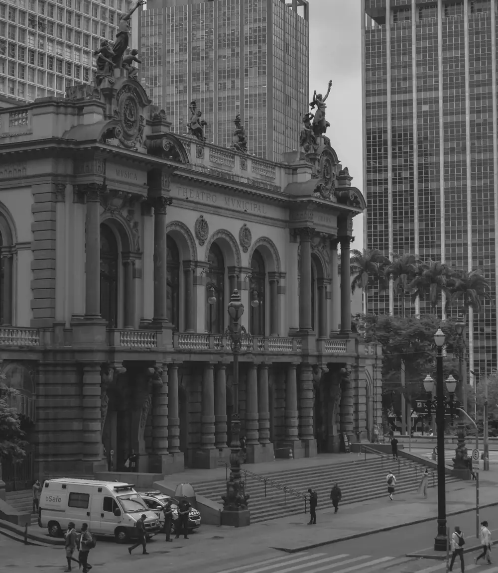 Fachada do Theatro Municipal de São Paulo, em preto e branco, entre edifícios altos